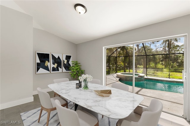 dining room featuring lofted ceiling, tile patterned flooring, and a healthy amount of sunlight