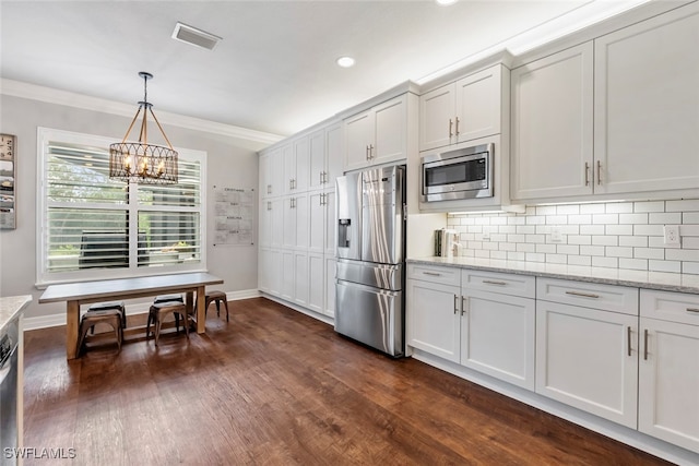 kitchen with white cabinets, appliances with stainless steel finishes, a chandelier, dark hardwood / wood-style floors, and light stone counters