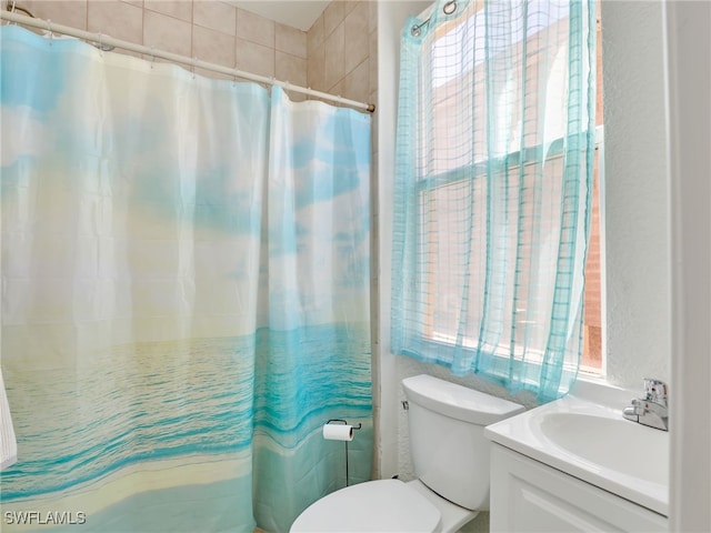 bathroom featuring walk in shower, plenty of natural light, vanity, and toilet