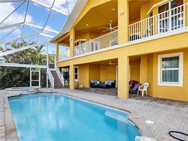 view of pool with an in ground hot tub, an outdoor hangout area, ceiling fan, glass enclosure, and a patio area