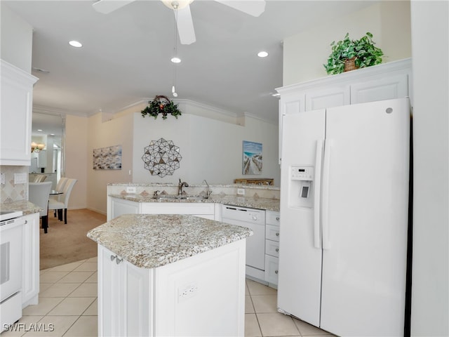 kitchen with white appliances, sink, a center island, white cabinets, and ornamental molding