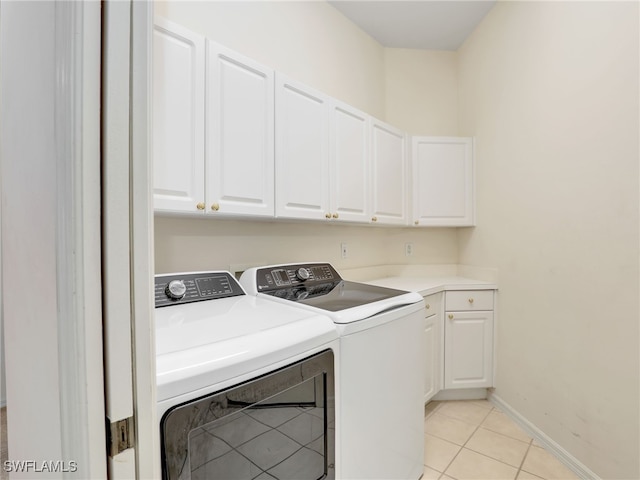 clothes washing area with cabinets, washing machine and dryer, and light tile patterned floors