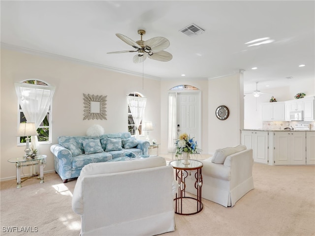 living room with crown molding, light colored carpet, and ceiling fan