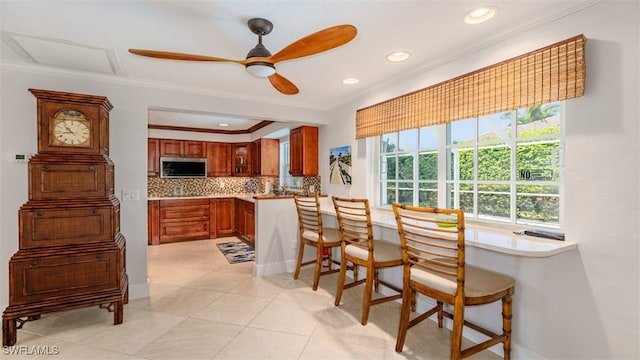 kitchen featuring ceiling fan, crown molding, kitchen peninsula, and tasteful backsplash