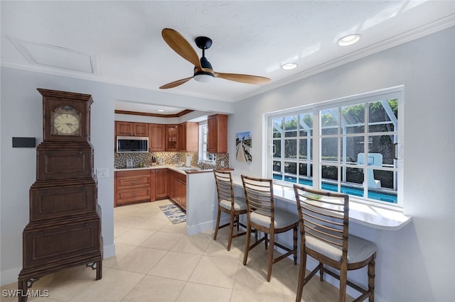 kitchen featuring sink, decorative backsplash, ornamental molding, light tile patterned floors, and ceiling fan