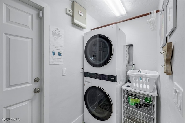 laundry room featuring stacked washer / drying machine and a textured ceiling