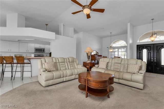 tiled living room featuring high vaulted ceiling and ceiling fan with notable chandelier