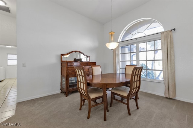 dining area featuring high vaulted ceiling and light carpet