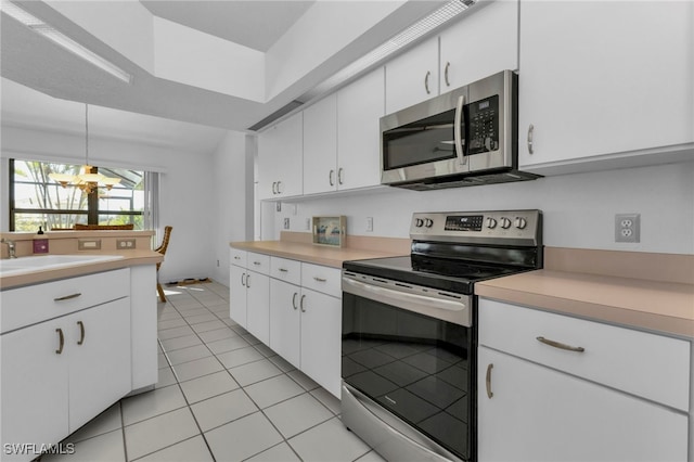 kitchen with light tile patterned flooring, white cabinetry, sink, appliances with stainless steel finishes, and decorative light fixtures