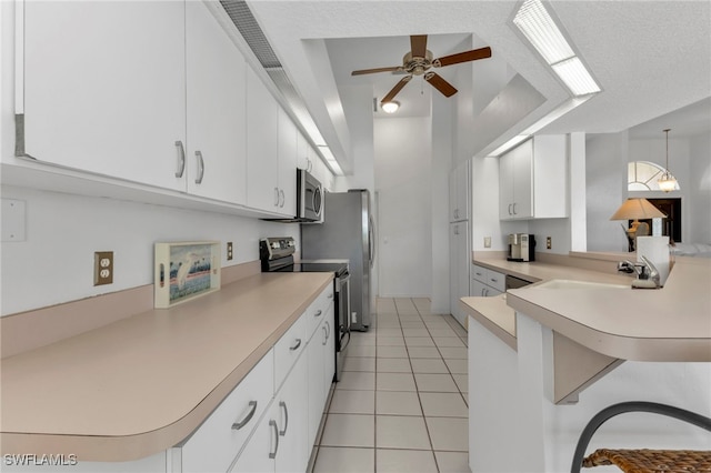 kitchen with white cabinetry, kitchen peninsula, appliances with stainless steel finishes, and a breakfast bar