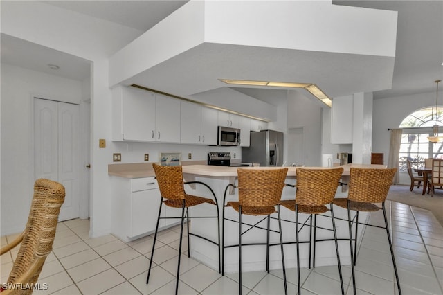 kitchen with white cabinetry, appliances with stainless steel finishes, light tile patterned floors, and a breakfast bar