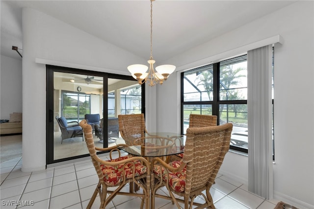 tiled dining room with ceiling fan with notable chandelier, a healthy amount of sunlight, and vaulted ceiling