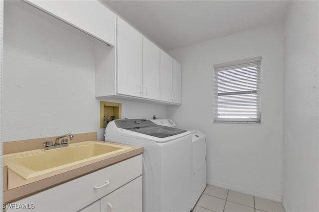 clothes washing area featuring sink, cabinets, washing machine and clothes dryer, and light tile patterned floors