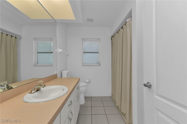 bathroom with toilet, vanity, a healthy amount of sunlight, and tile patterned floors