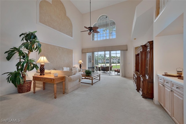 living room featuring ceiling fan, light carpet, and a towering ceiling