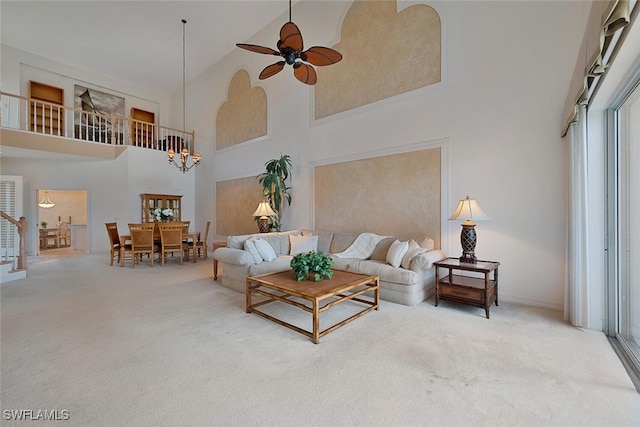 carpeted living room featuring high vaulted ceiling and ceiling fan with notable chandelier