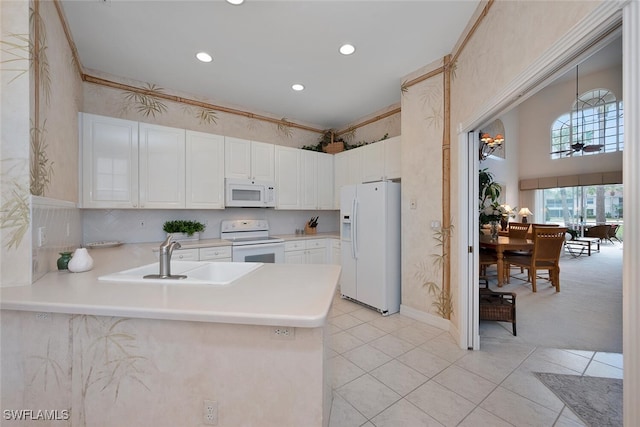 kitchen with white cabinetry, sink, kitchen peninsula, and white appliances