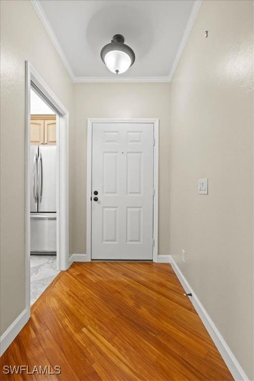 doorway with light wood-type flooring, baseboards, and ornamental molding