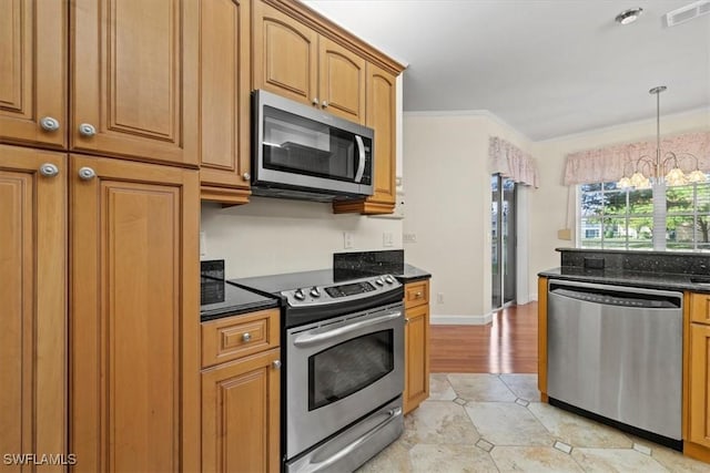 kitchen with dark stone countertops, hanging light fixtures, stainless steel appliances, a notable chandelier, and ornamental molding