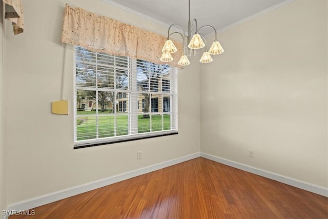 unfurnished dining area with an inviting chandelier, crown molding, wood finished floors, and baseboards