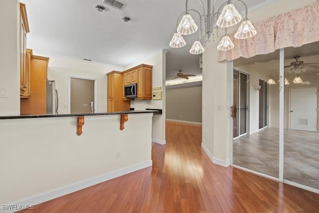 kitchen featuring visible vents, dark countertops, appliances with stainless steel finishes, light wood finished floors, and ceiling fan