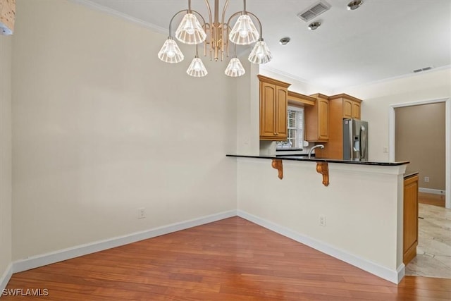 kitchen featuring dark countertops, visible vents, stainless steel refrigerator with ice dispenser, and light wood-type flooring