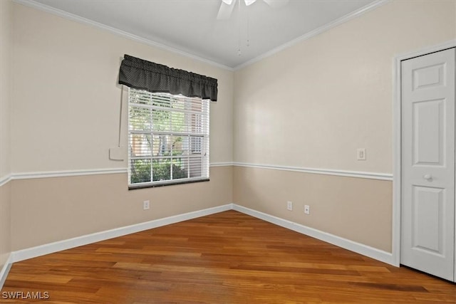 unfurnished room featuring ceiling fan, wood finished floors, baseboards, and ornamental molding