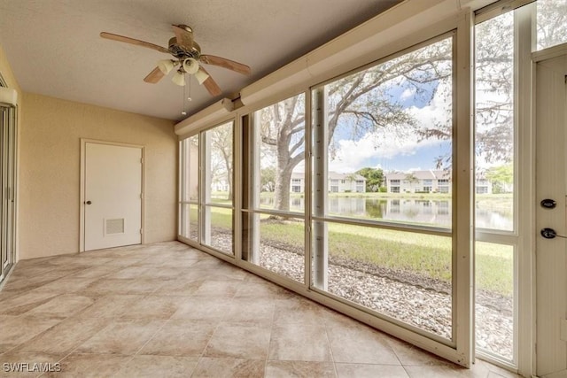 unfurnished sunroom featuring visible vents, a water view, and ceiling fan