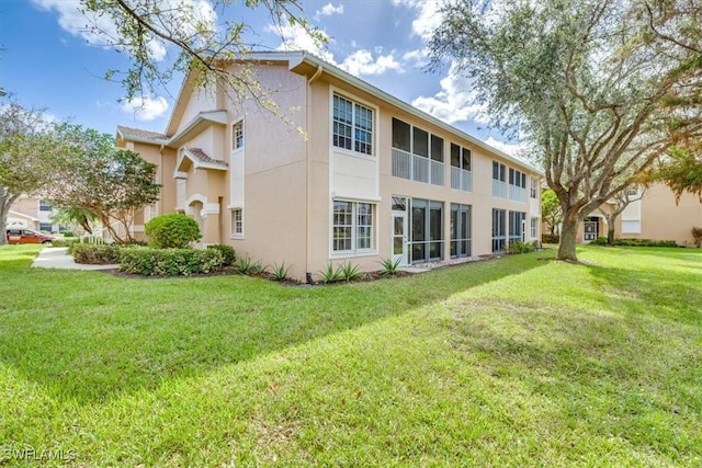 rear view of property with a yard and stucco siding