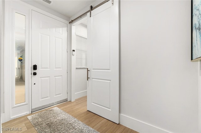 entrance foyer with a barn door and light hardwood / wood-style floors