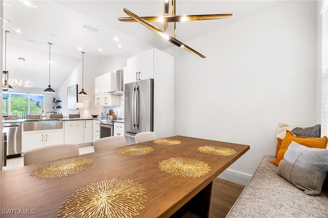 dining area with sink, light hardwood / wood-style flooring, and vaulted ceiling