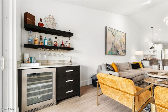 bar featuring light wood-type flooring, wine cooler, pendant lighting, and lofted ceiling