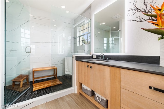 bathroom with walk in shower, vanity, and wood-type flooring