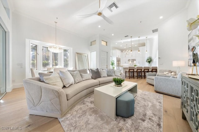 living room with ornamental molding, ceiling fan with notable chandelier, and light wood-type flooring