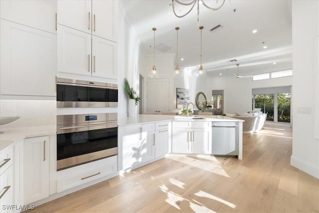 kitchen with pendant lighting, white cabinetry, light hardwood / wood-style floors, kitchen peninsula, and stainless steel appliances