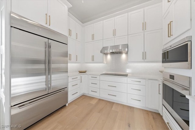 kitchen featuring built in appliances, white cabinetry, light hardwood / wood-style floors, and range hood