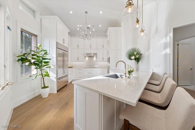 kitchen featuring white cabinetry, sink, pendant lighting, and stainless steel built in refrigerator