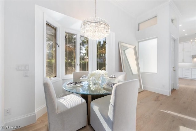 dining space featuring light hardwood / wood-style floors, an inviting chandelier, and ornamental molding