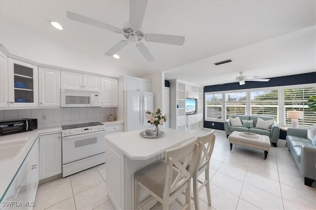 kitchen with light tile patterned floors, white appliances, and white cabinetry