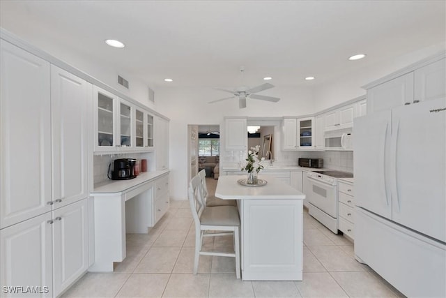 kitchen with white appliances, a kitchen island, white cabinetry, a breakfast bar, and light tile patterned floors