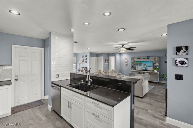 kitchen featuring a kitchen island with sink, wood-type flooring, sink, stainless steel dishwasher, and white cabinetry