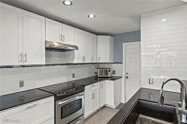 kitchen featuring stainless steel range with electric stovetop, sink, light wood-type flooring, white cabinets, and tasteful backsplash