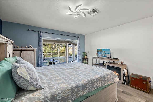 bedroom with light hardwood / wood-style flooring, access to outside, and ceiling fan