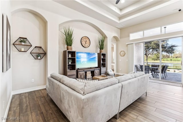 7821 Ashton Rd, Naples, FL 34113 - living room featuring hardwood / wood-style flooring, a tray ceiling, arched walkways, ceiling fan, and a high ceiling