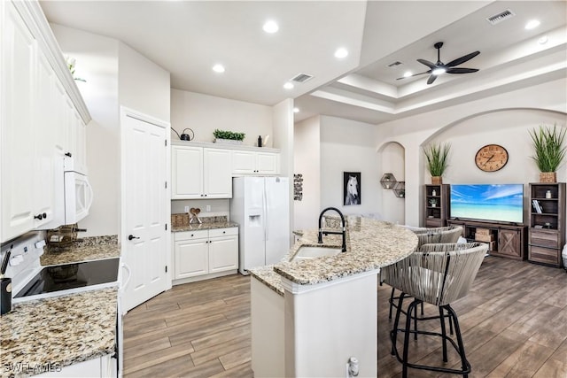 7821 Ashton Rd, Naples, FL 34113 - kitchen with white appliances, a ceiling fan, a kitchen bar, light wood-style flooring, and a kitchen island with sink