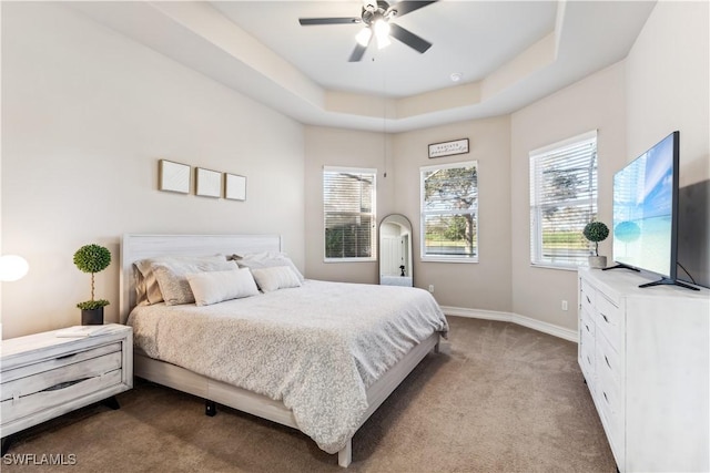 bedroom with light carpet, a tray ceiling, and ceiling fan