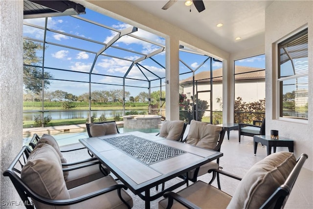 view of patio featuring a swimming pool with hot tub, a water view, ceiling fan, and a lanai