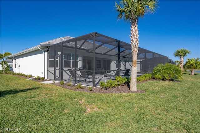 back of house featuring a patio, a lawn, a lanai, and stucco siding