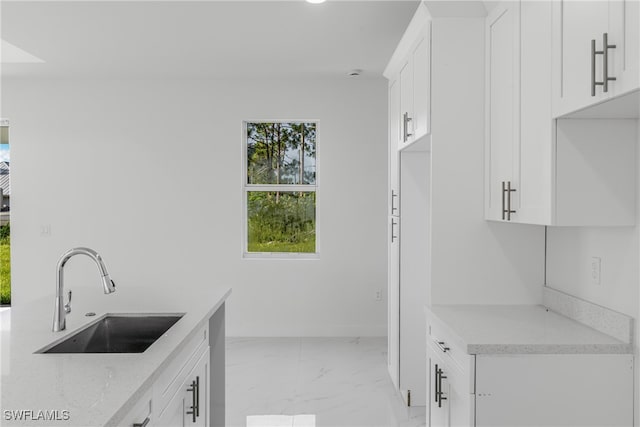 kitchen with sink, white cabinets, and light stone counters