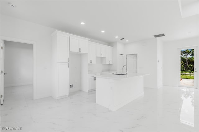 kitchen with white cabinetry, sink, and a kitchen island with sink